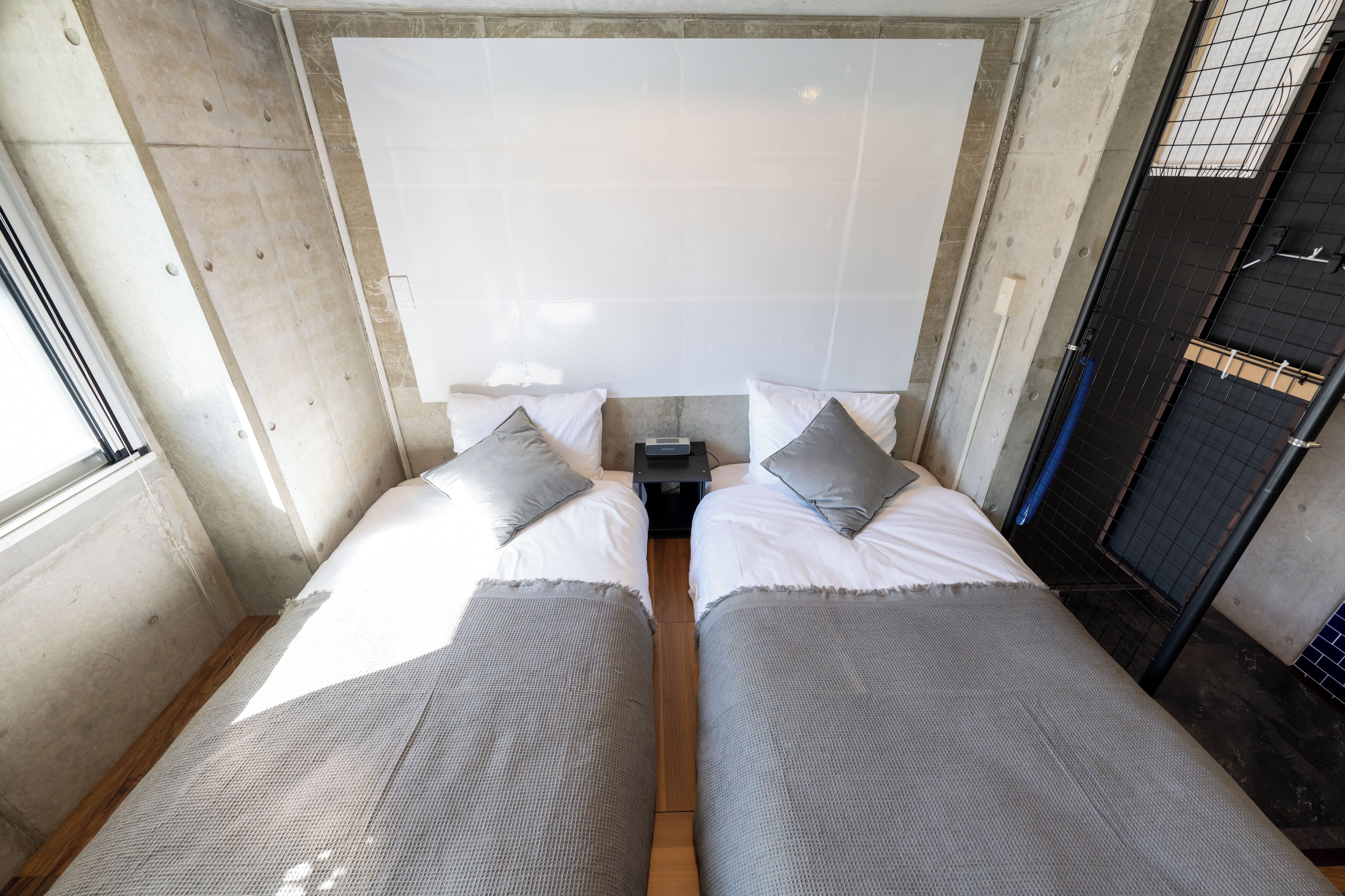 Een kamer met twee bedden, elk voorzien van een kussen en een klein tafeltje ertussen.