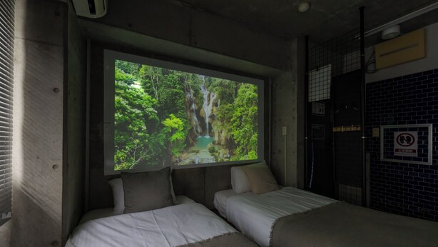 Una habitación con dos camas, un ventanal que muestra un paisaje de bosque y vistas al exterior.