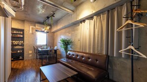 Una sala de estar moderna con sofá de cuero, mesa de centro de madera y zona de comedor con mesa y sillas.