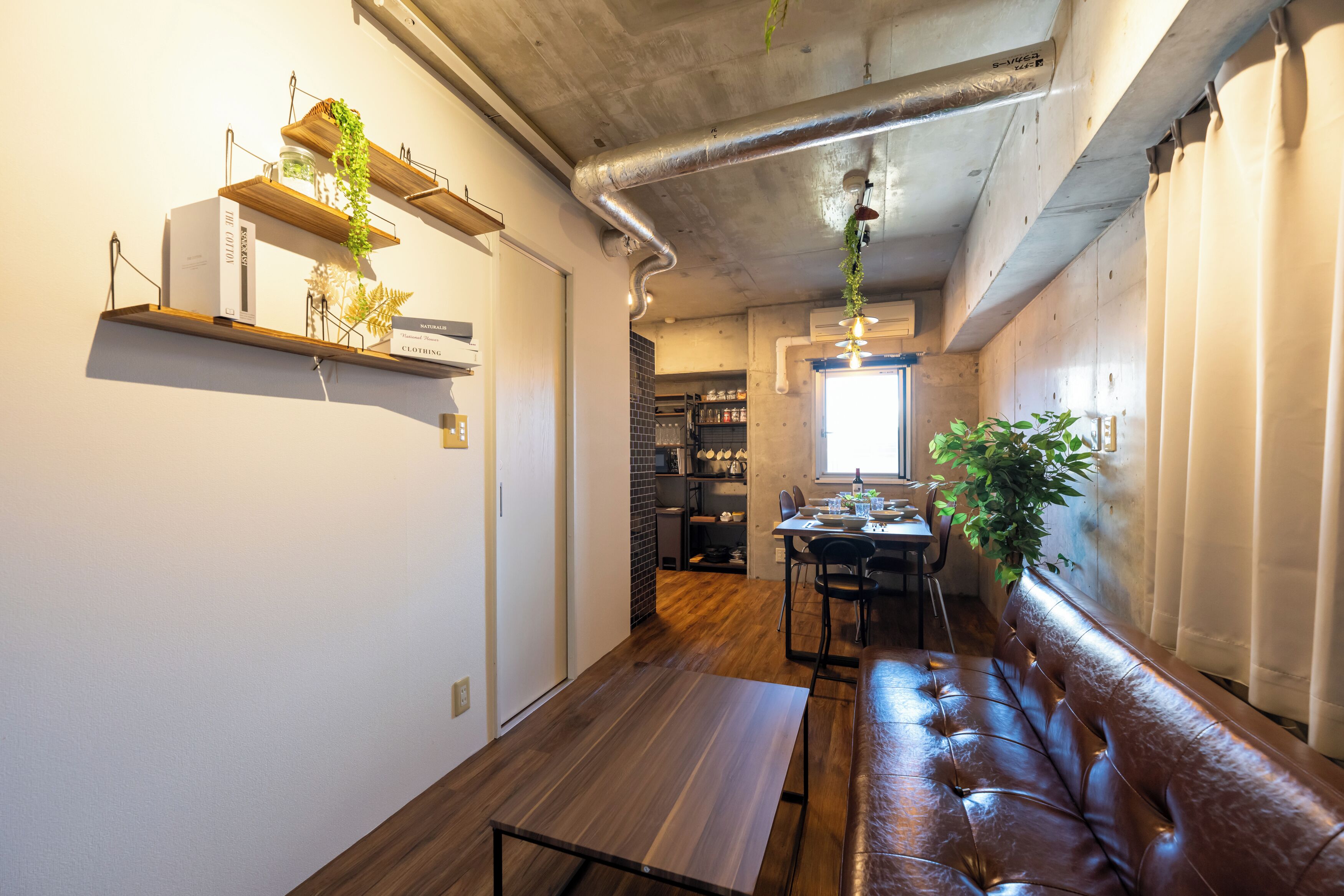 A modern kitchen with wooden shelves, a dining area with a bench, and a visible kitchen counter.