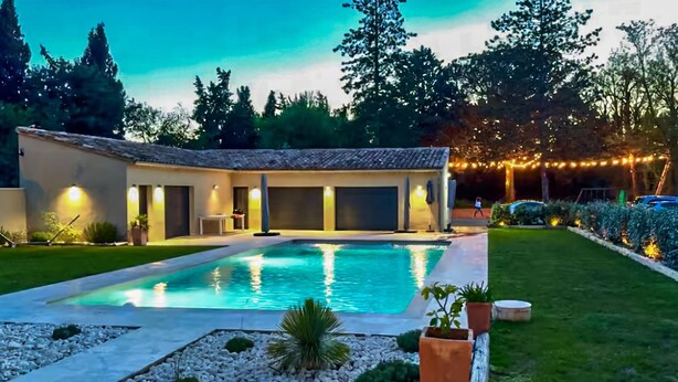 A swimming pool with a tiled deck, surrounded by a well-maintained lawn and potted plants. - Gorgeous home in Noves (Noves)