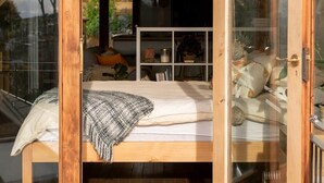 Une chambre confortable avec un lit, une petite table et une étagère ornée d’objets décoratifs.