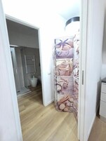 Un pasillo con suelo de madera, una puerta blanca y un cartel con motivos náuticos en la pared.