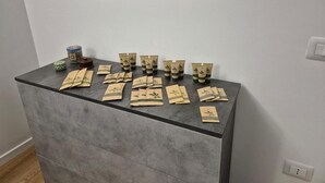 A room with a grey cabinet displaying neatly arranged packets and a small decorative item on top. - Flamingo Houses (Quartu Sant'Elena)