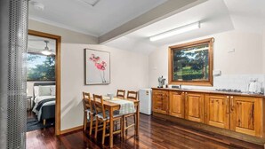 Une cuisine moderne avec des meubles en bois, un coin repas comprenant une table et des chaises, et une grande fenêtre donnant sur un paysage verdoyant.