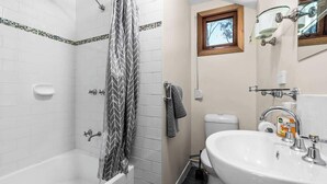 Une salle de bain avec douche, toilettes et lavabo.