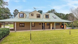 Une maison à deux étages avec un porche couvert, une cheminée et un petit garage attenant.