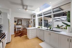 Eine moderne Küche mit weißen Schränken, einem großen Fenster und einem Deckenventilator.