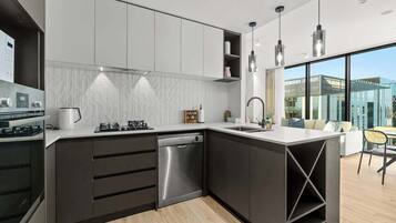 A modern kitchen with dark cabinetry, a dishwasher, and a built-in oven.