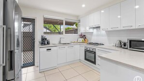 A modern kitchen with white cabinets, a stainless steel refrigerator, a gas stove, and a microwave. - Urban Sanctuary Condo in Norwood 2b1b+free parking (Norwood)