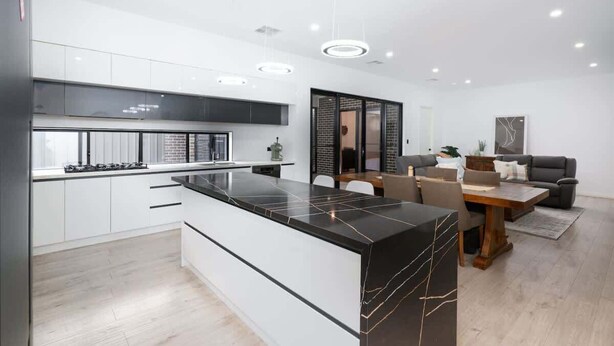 A modern kitchen with white cabinets, a black marble island, and recessed lighting. - Large Family entire house adelaide 4br2ba (Rostrevor)