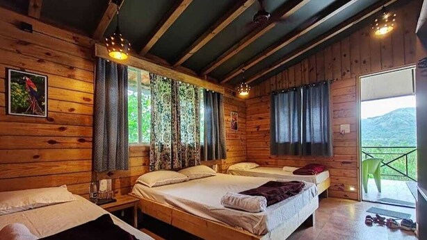 Une cabane en bois avec deux lits, un balcon et une vue sur l’extérieur.