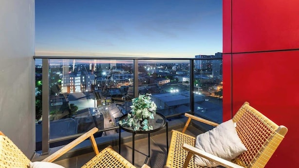 A balcony with wicker chairs, a small table, and a potted plant. - Comfort city view apartment Central Adelaide (Adelaide)
