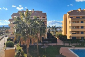 A hotel with multiple floors, a swimming pool, and palm trees. - Spacious Appartment in Dénia - 2min from Beach. (VC)