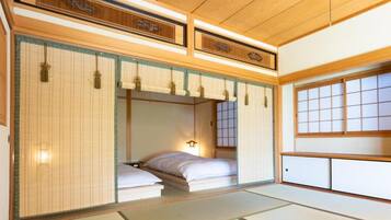 Una habitación japonesa tradicional con suelo de tatami, cama de madera baja, puertas correderas y un mamparas shoji.