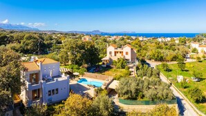A coastal residential area with houses, a swimming pool, and a view of the sea. - Villa Aspa in Prines (Rethymno)