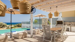 An outdoor patio with a pool, wicker furniture, and a grill area.