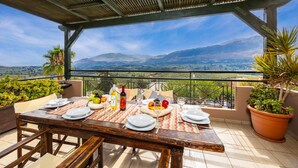 A terrace with a table set for a meal, overlooking a mountainous landscape. - Aloni Villa in Apokoronos (Apokoronas)