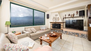 A living room with a large window, a fireplace, a TV, and a sofa. - Aloni Villa in Apokoronos (Apokoronas)