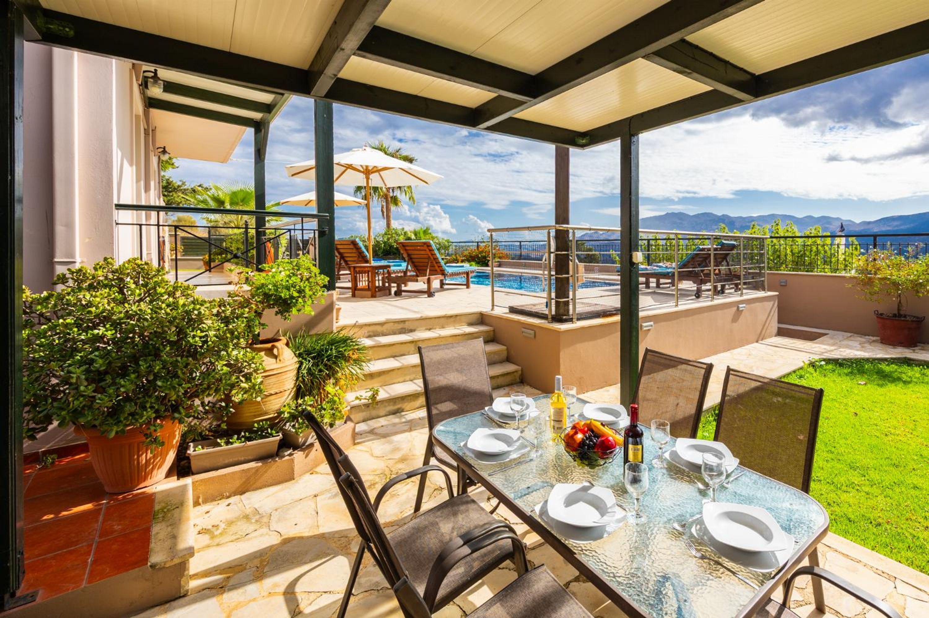 An outdoor dining area with a view of the sea, a pool, and a covered patio.