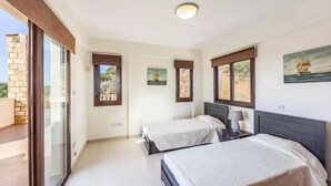 A bedroom with two beds, a balcony, and a view of the sea. - Villa Aqua View in Kissonerga (Pegeia)