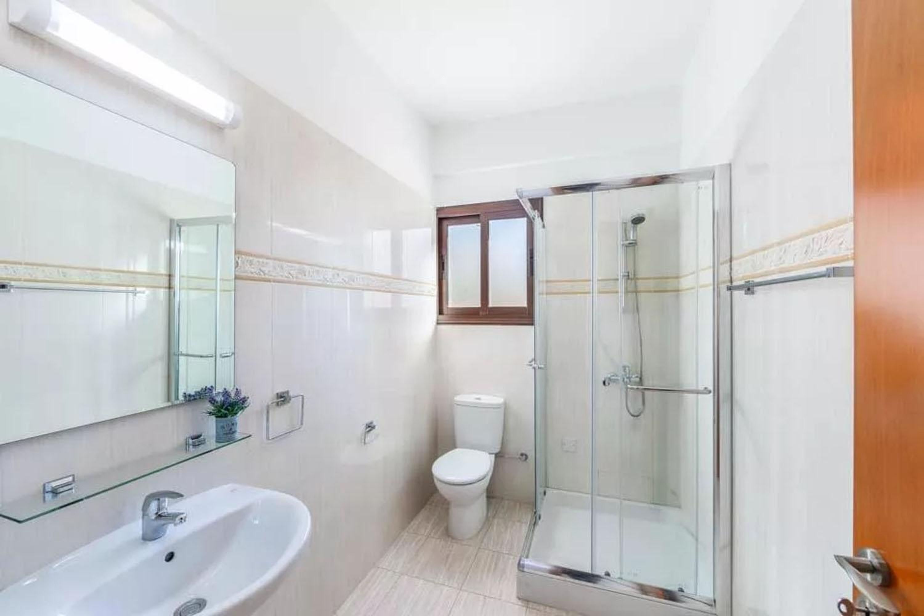 A compact bathroom with a glass-enclosed shower, a white sink, and a toilet.