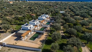 A coastal hotel with multiple white buildings, a swimming pool, and olive groves in the background. - Villa Aurelia in Afandou (Rhodes)