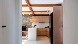 Une cuisine moderne avec des meubles en bois, un îlot central et un mur d’accent en pierre.