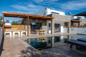 A modern house with a swimming pool, outdoor seating, and a stone facade. - Villa Amethysta in Afandou (Rhodes)