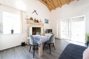 A dining area with a stone fireplace, a table set for four, and a view through a glass door. - Villa Bella Vista in Sveti Filip i Jakov (Sveti Filip i Jakov)