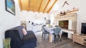 A cozy living room with a dark blue sofa, a dining table with chairs, a fireplace, and a kitchen in the background. - Villa Bella Vista in Sveti Filip i Jakov (Sveti Filip i Jakov)