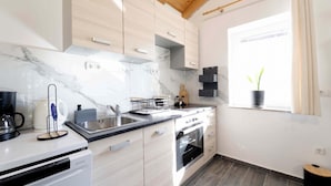 A modern kitchen with light wood cabinets, a marble countertop, and a built-in oven. - Villa Bella Vista in Sveti Filip i Jakov (Sveti Filip i Jakov)