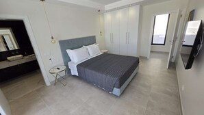 Ein modernes Schlafzimmer mit Bett, Nachttischen, einem Kleiderschrank und einem Fernseher.