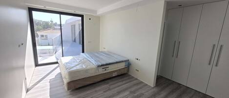 Une chambre à coucher comprenant un lit, une armoire et une porte-fenêtre coulissante donnant sur un espace extérieur.