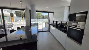 Eine moderne Küche mit Glastür, die auf eine Terrasse führt.