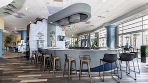 Un espace bar moderne avec un comptoir incurvé, des tabourets de bar et un mur orné de motifs.