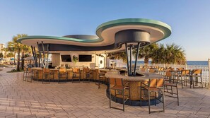 Un espace bar extérieur doté d’un toit incurvé, de sièges et offrant une vue sur la mer.