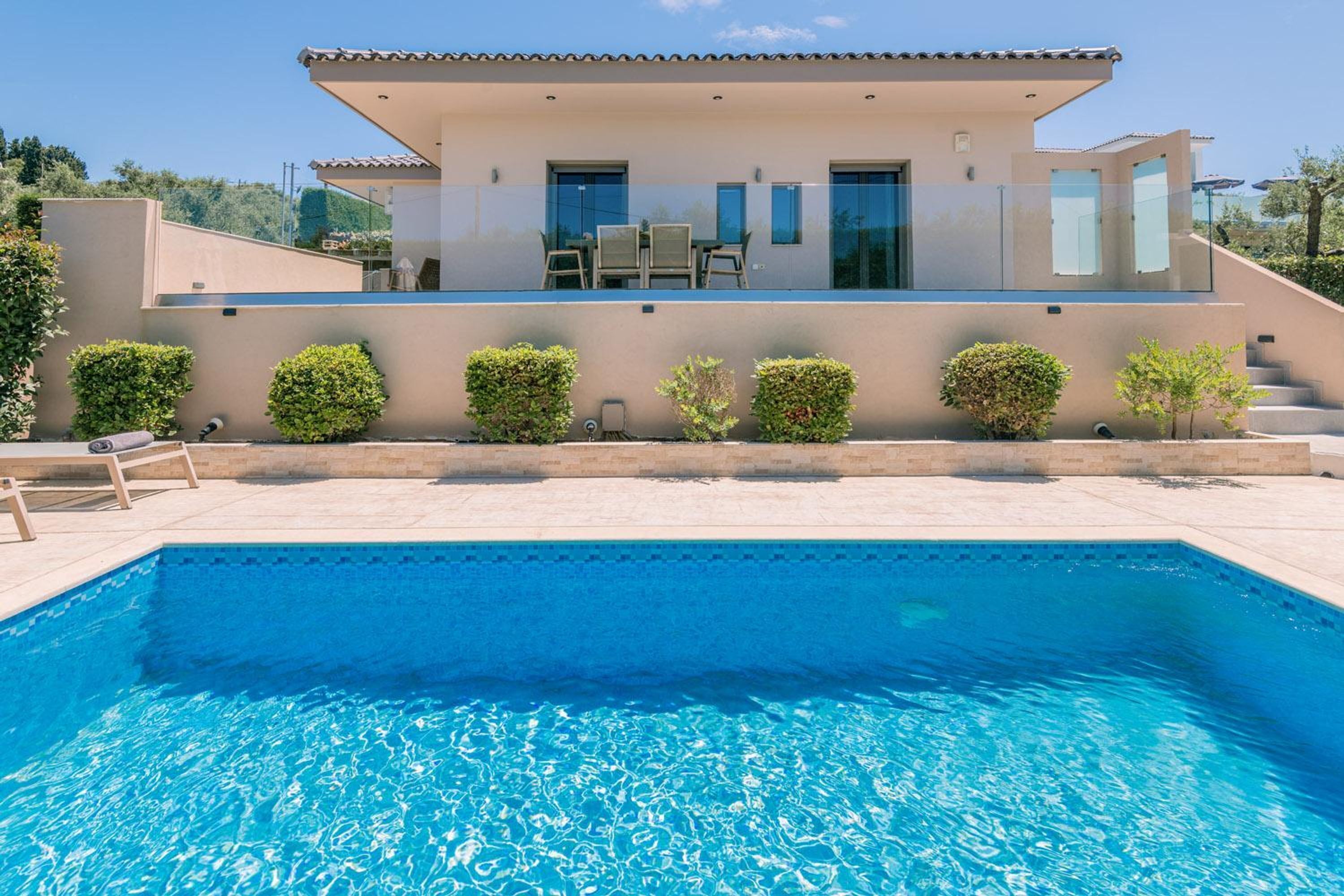 A modern house with a swimming pool, a covered patio, and a view of the surrounding landscape.