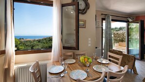 A dining area with a table set for four, a view of the sea, and a balcony with a view of the sea. - Villa Elpida in Gaios (Paxos)