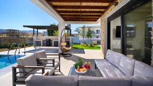 Ein moderner Außenbereich mit Pool, Sitzgelegenheiten und Blick auf die umliegende Landschaft.