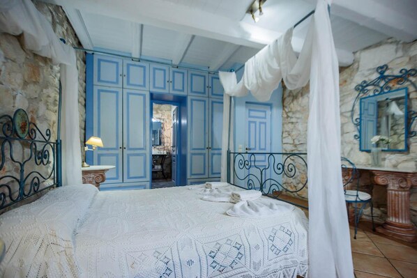 Ein Schlafzimmer mit einem großen Bett, blauen Schränken, einer Steinwand und einem Spiegel.