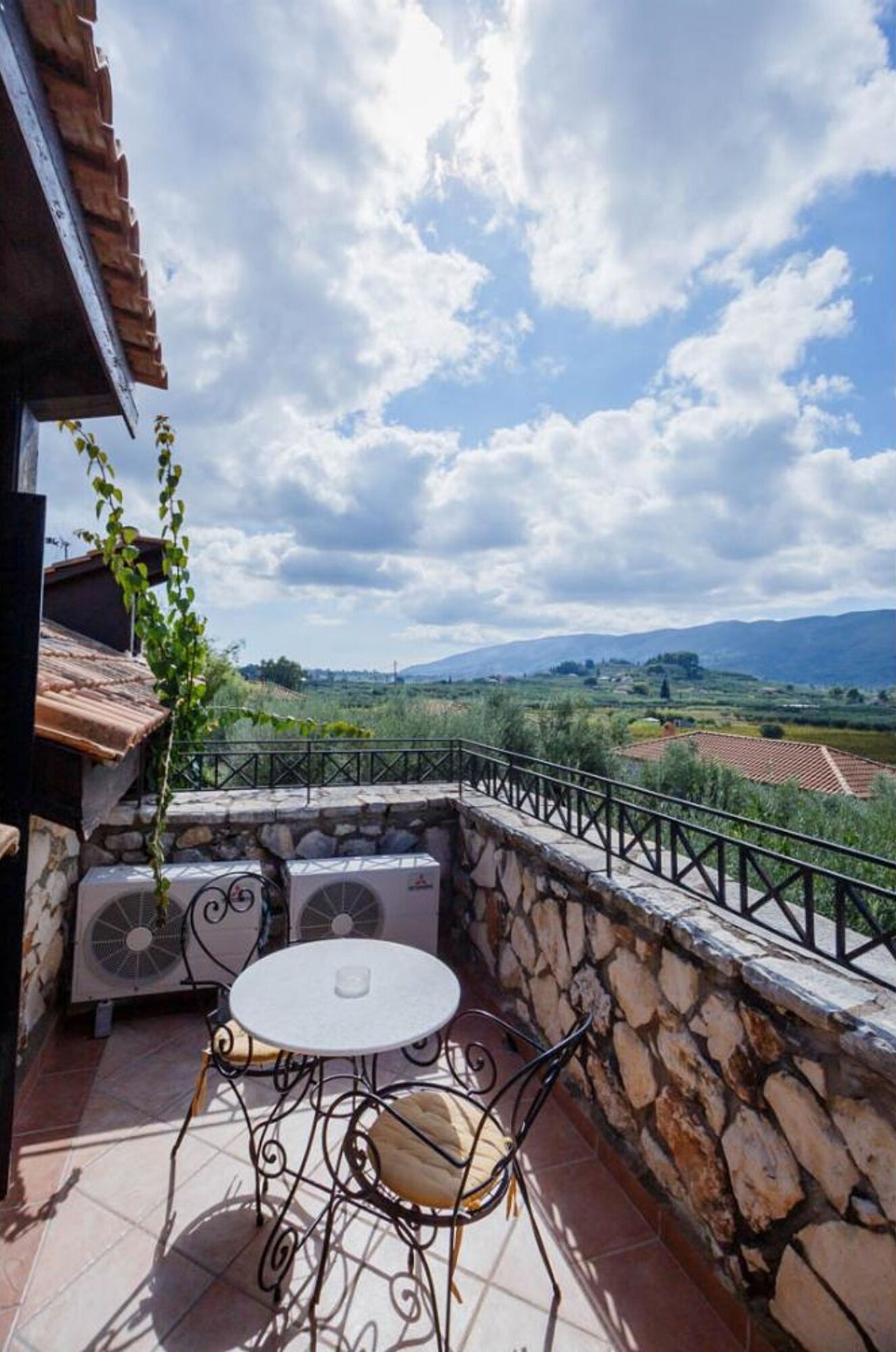 A patio with a stone wall, a table, and two chairs.