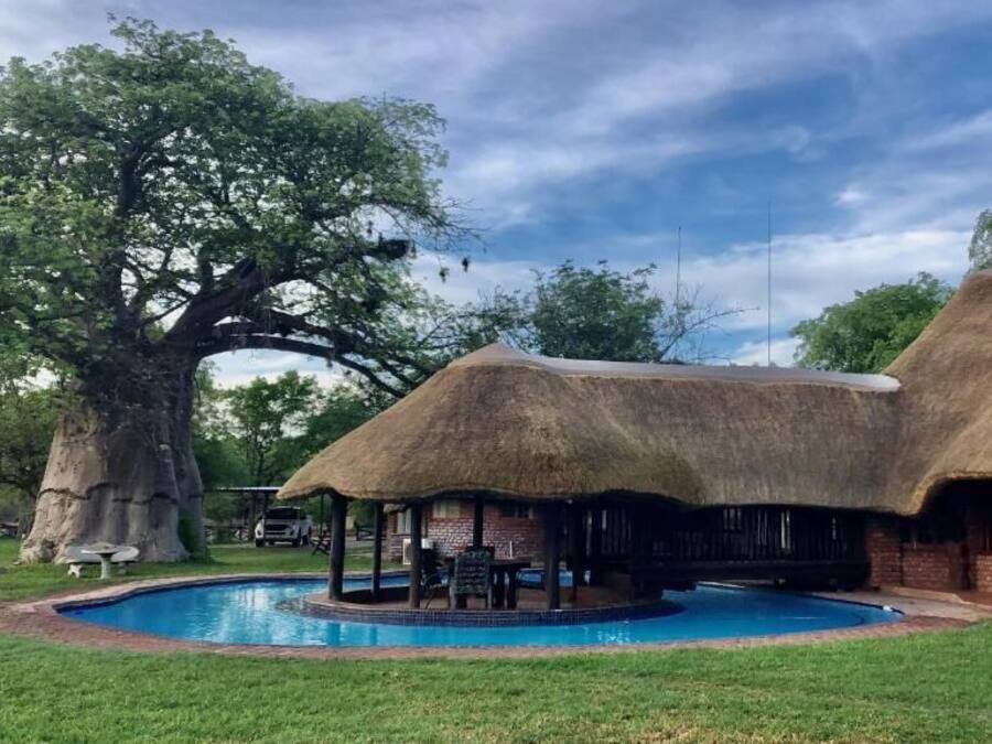 A thatched-roof building with a pool in front.