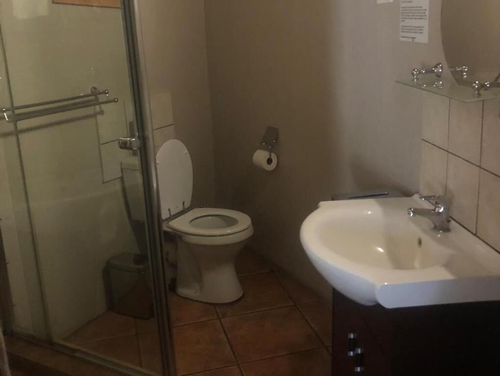A bathroom with a toilet, a glass shower enclosure, and a sink.