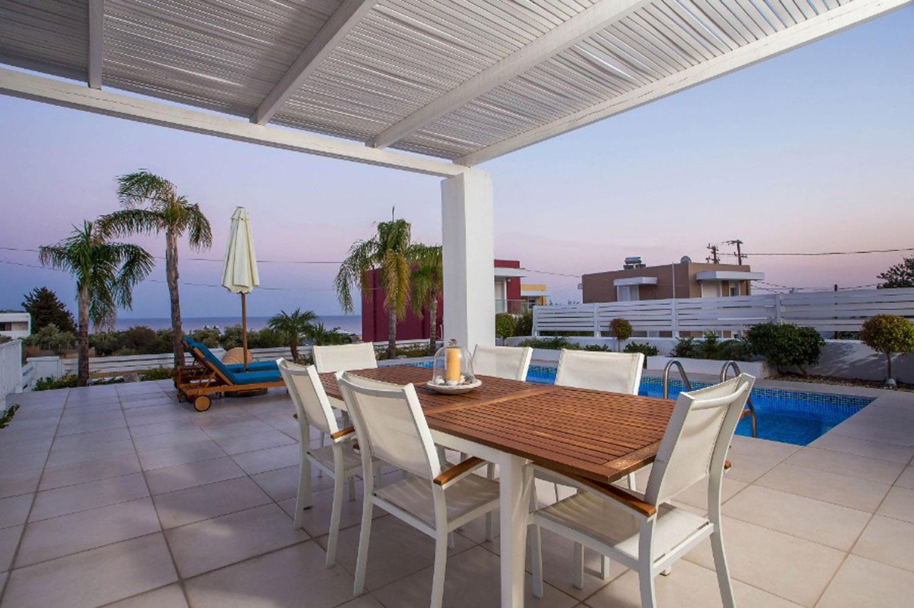 Un espace extérieur abrité comprenant une piscine, une table à manger avec des chaises et des fauteuils de relaxation.