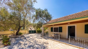A stone-paved courtyard with a building featuring a tiled roof and green shutters. - Villa Old Vineyard in Paxi (Paxos)