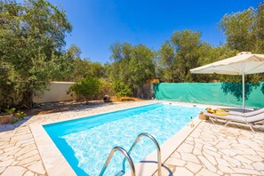 A swimming pool with stone tiles, a metal ladder, and lounge chairs with an umbrella. - Villa Old Vineyard in Paxi (Paxos)