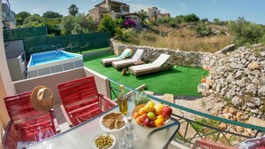 En terrasse med pool, liggestole og et bord med frugt og drikkevarer.