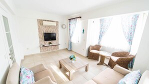 A living room with a TV, sofa, coffee table, and wicker chairs. - Villa Garden Island in Dalyan (Ortaca)