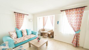 A bright living room with a sofa, coffee table, and wicker chairs. - Villa Garden Island in Dalyan (Ortaca)